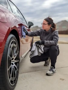 Britinee wiping off car wax from a red Mercedes in mansfield texas